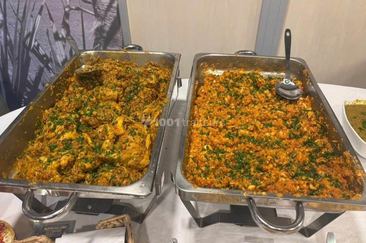 Deux plats en inox contenant des préparations épicées garnies de persil, présentés sur une table de buffet.