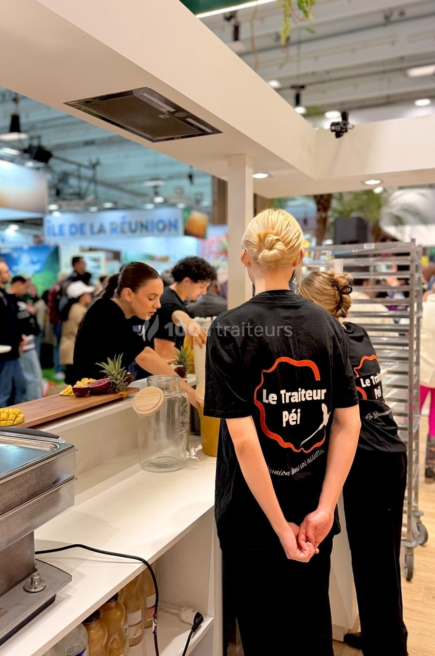 Des employés préparent des plats dans un stand de restauration lors d'un événement ou d'une foire.