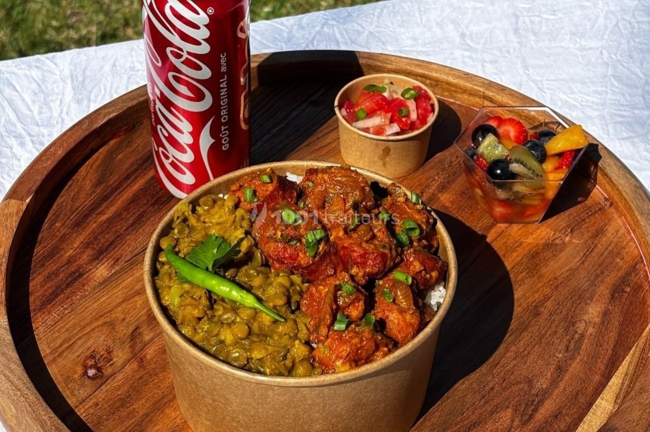 Repas servi sur un plateau en bois avec un bol de curry, des lentilles, une salade de fruits et une canette de soda.