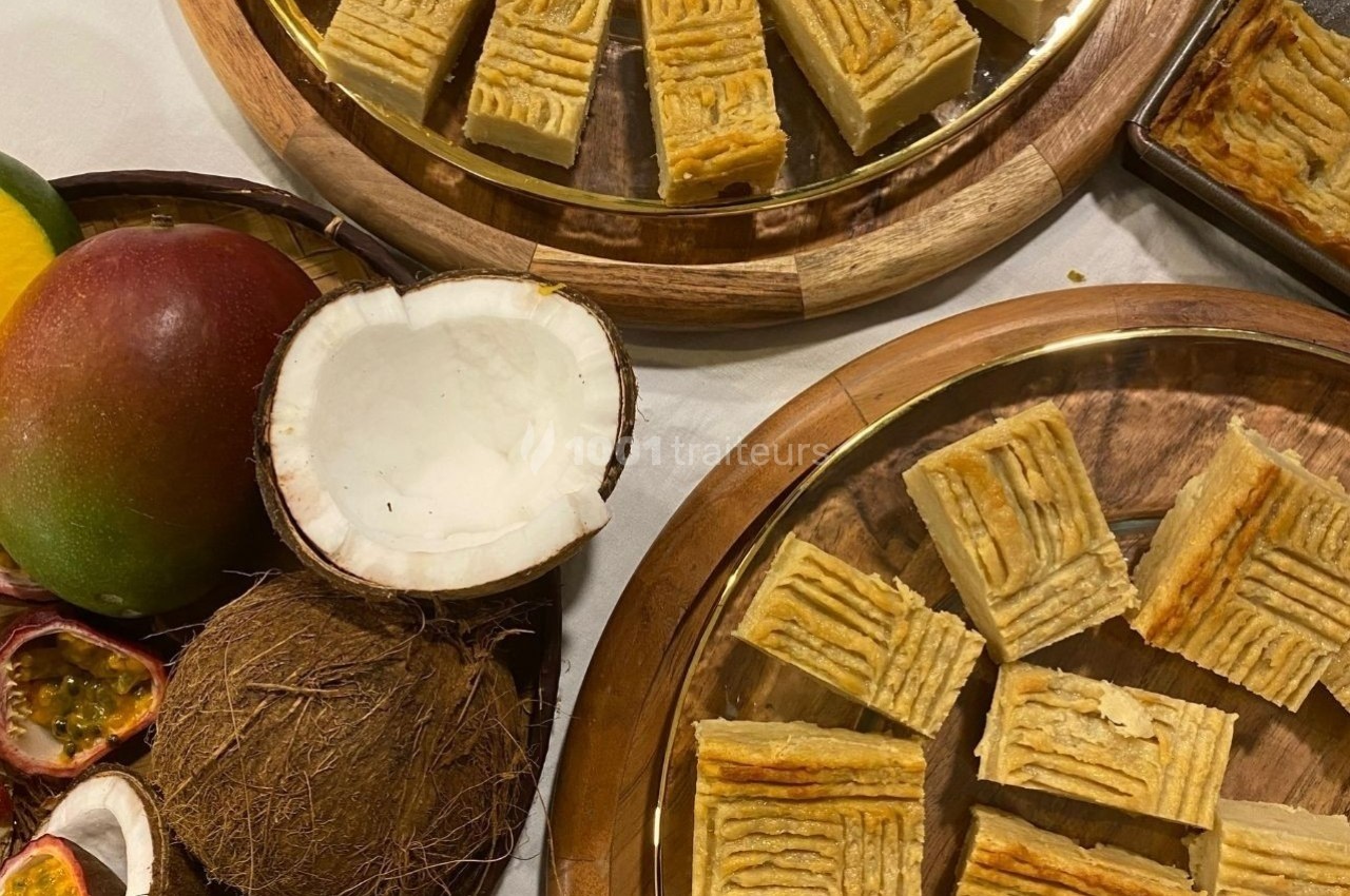Assortiment de gâteaux dorés sur des plateaux en bois, entourés de fruits tropicaux comme noix de coco, mangue et fruits de…