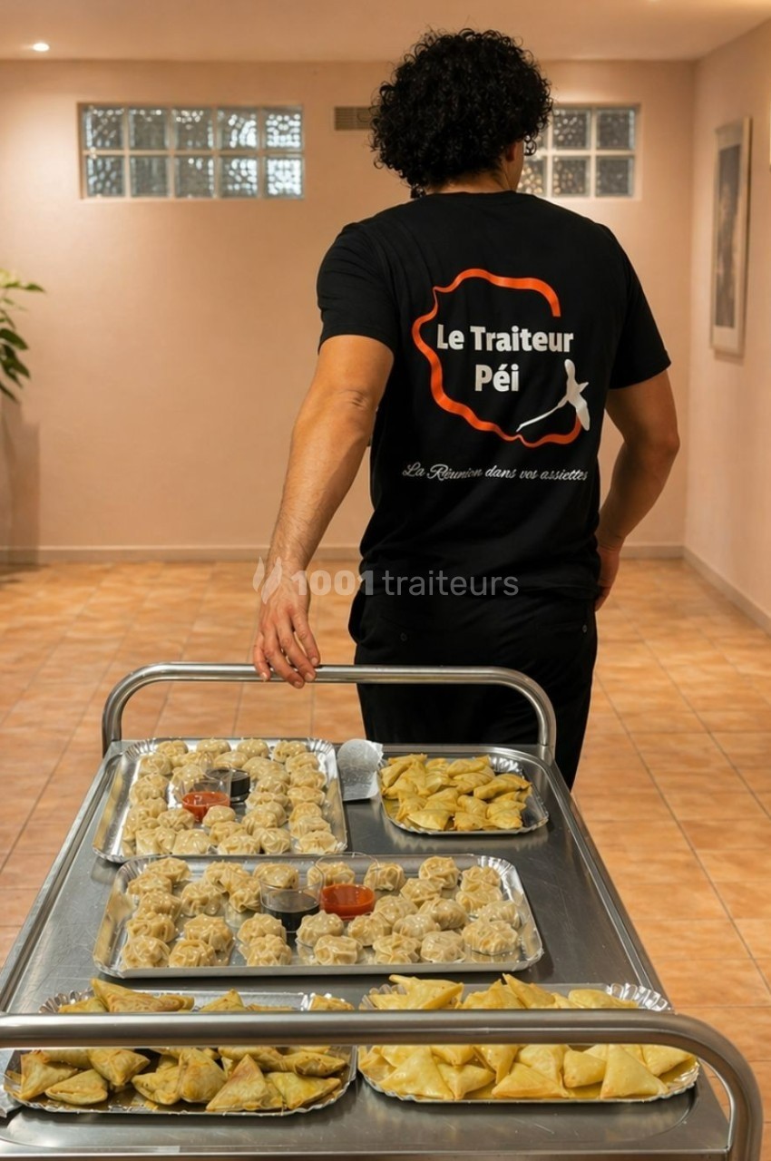 Un traiteur transporte un chariot rempli de plateaux contenant des bouchées et amuse-bouches dans un couloir.