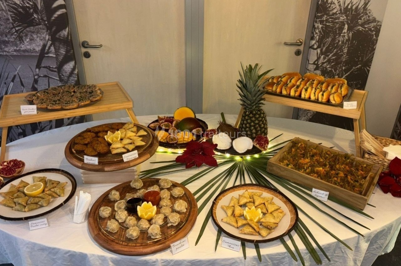 Table garnie de divers plats et desserts exotiques, présentés sur des plateaux en bois avec des décorations tropicales.