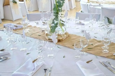 Miniature Mas Adamon Location #6 Table dressée en extérieur avec nappes blanches, verres et décorations florales, entourée de chaises en bois.