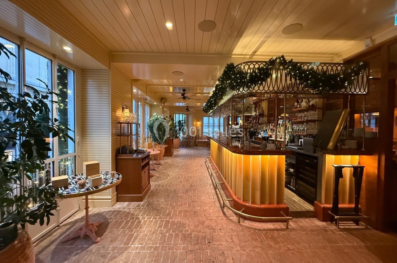 Intérieur d'un restaurant chaleureux avec bar éclairé, décorations lumineuses et plantes en arrière-plan.