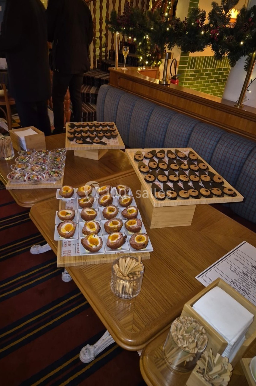 Table garnie de pâtisseries variées, dont des tartelettes et biscuits, dans un décor festif avec guirlandes de Noël.