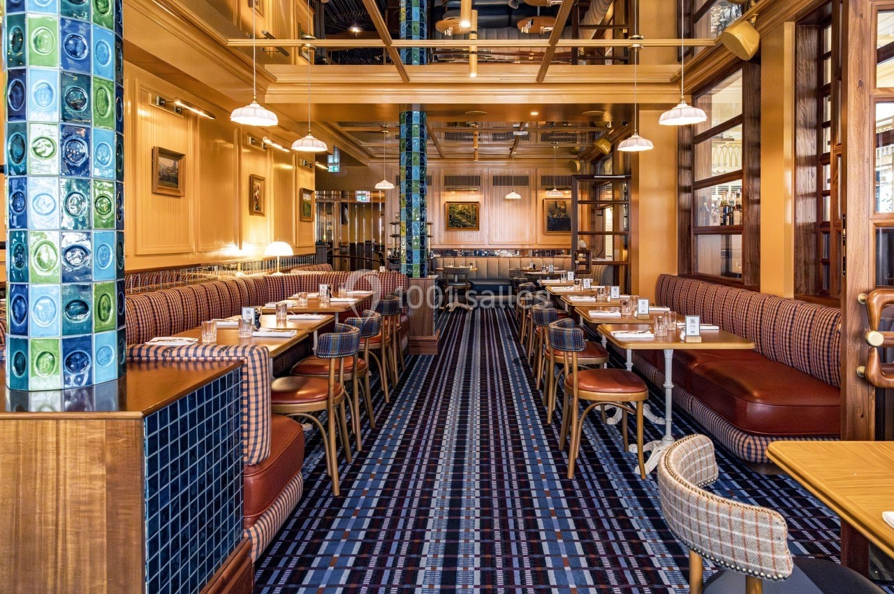 Salle de restaurant élégante avec tables en bois, banquettes rembourrées et décoration intérieure chaleureuse.