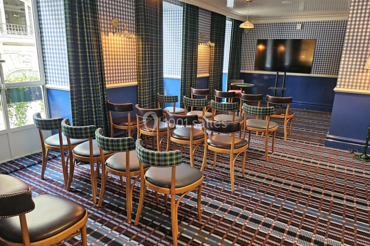 Salle de réunion lumineuse avec des chaises en bois disposées face à un écran, décorée de motifs à carreaux.