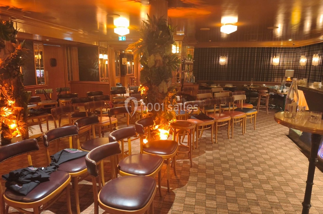 Salle aménagée avec des rangées de chaises en cuir brun, éclairage chaleureux et décorations végétales.