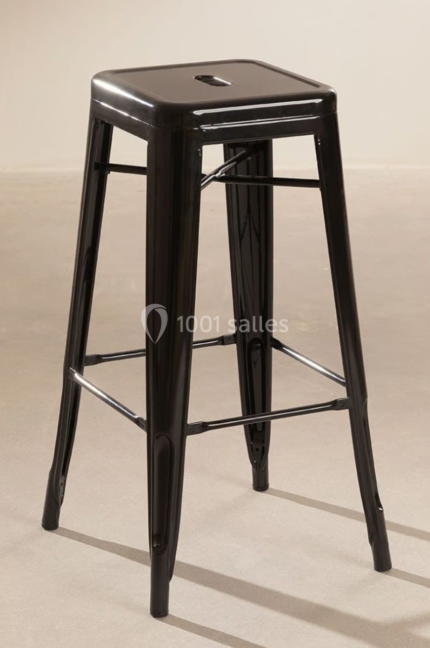 Tabouret haut en métal noir avec assise carrée et repose-pieds, posé sur un sol beige.