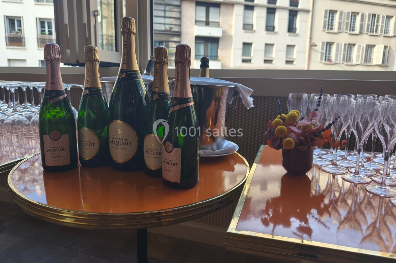 Bouteilles de champagne et flûtes vides disposées sur des tables dans un cadre intérieur lumineux.
