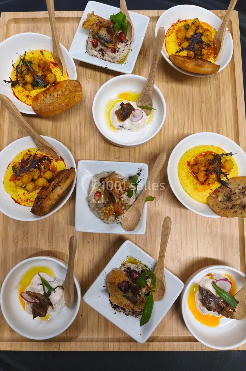 Plateau en bois avec plusieurs petites assiettes contenant des amuse-bouches variés et des cuillères en bois.