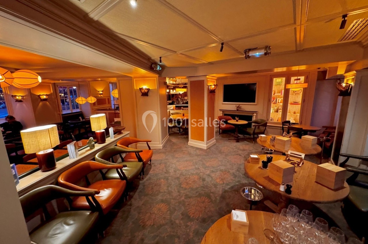 Salle de restaurant chaleureuse avec éclairage tamisé, tables en bois, chaises confortables et décoration élégante.