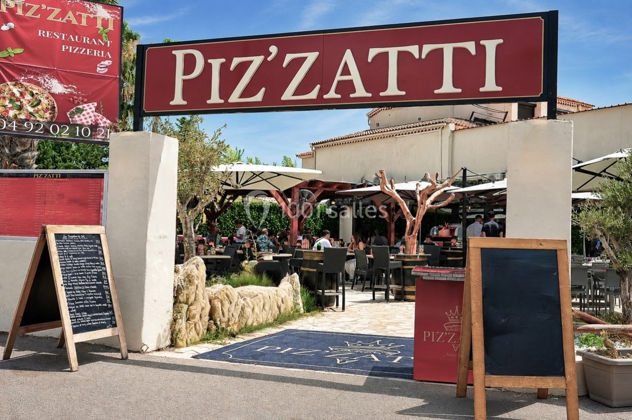 Entrée d'une pizzeria avec terrasse extérieure, tables occupées et enseigne ’Piz'zatti’ visible au-dessus.