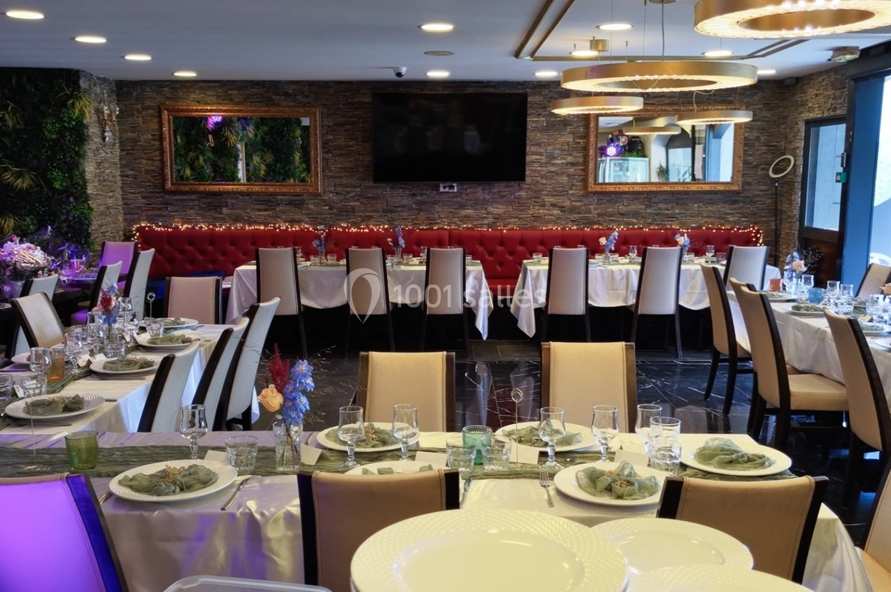 Salle de restaurant élégamment décorée avec des tables dressées pour un repas, chaises beige et banquettes rouges.