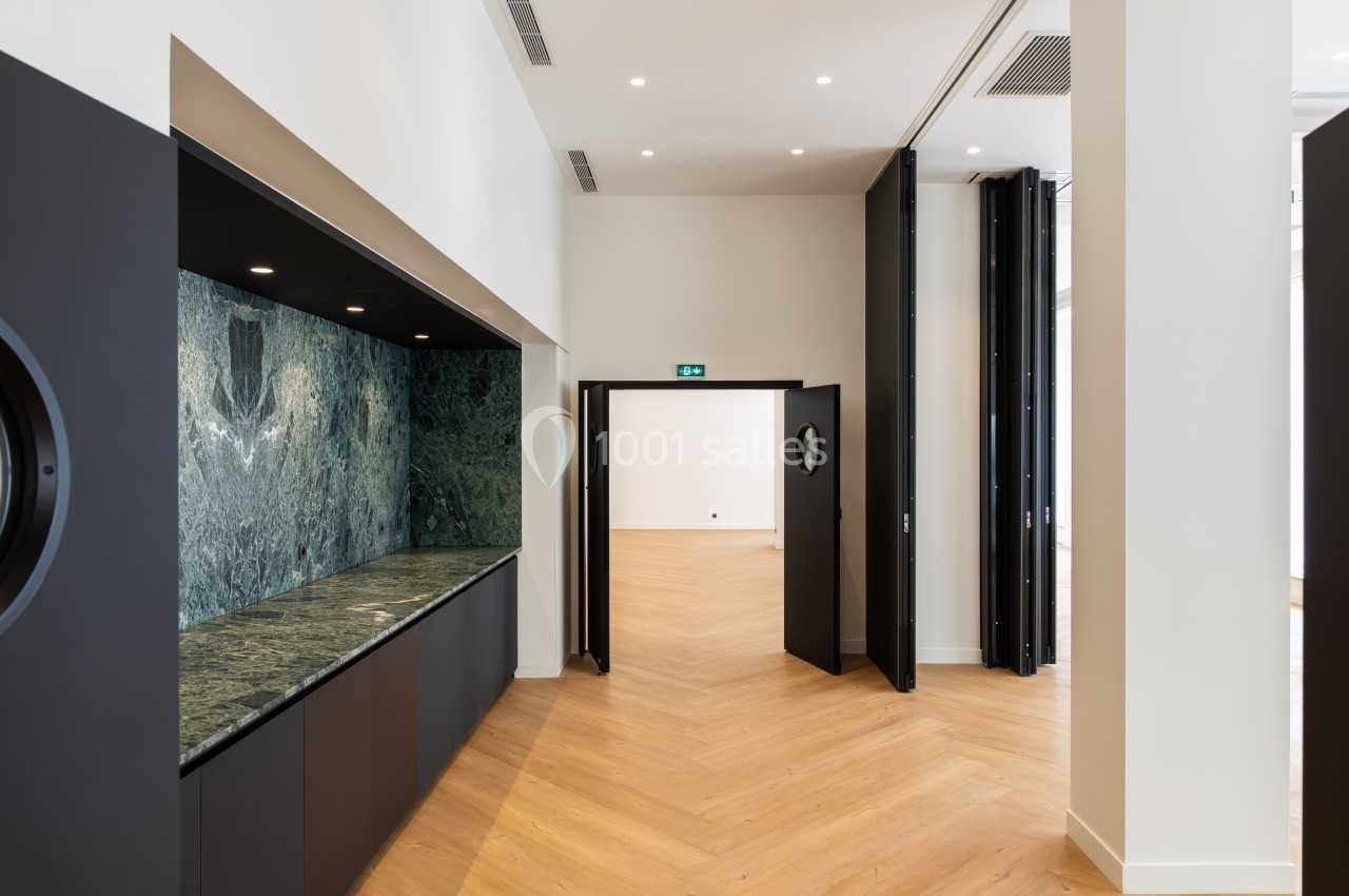 Vue intérieure d'une pièce lumineuse avec parquet en bois clair, murs blancs et un comptoir en marbre vert foncé.