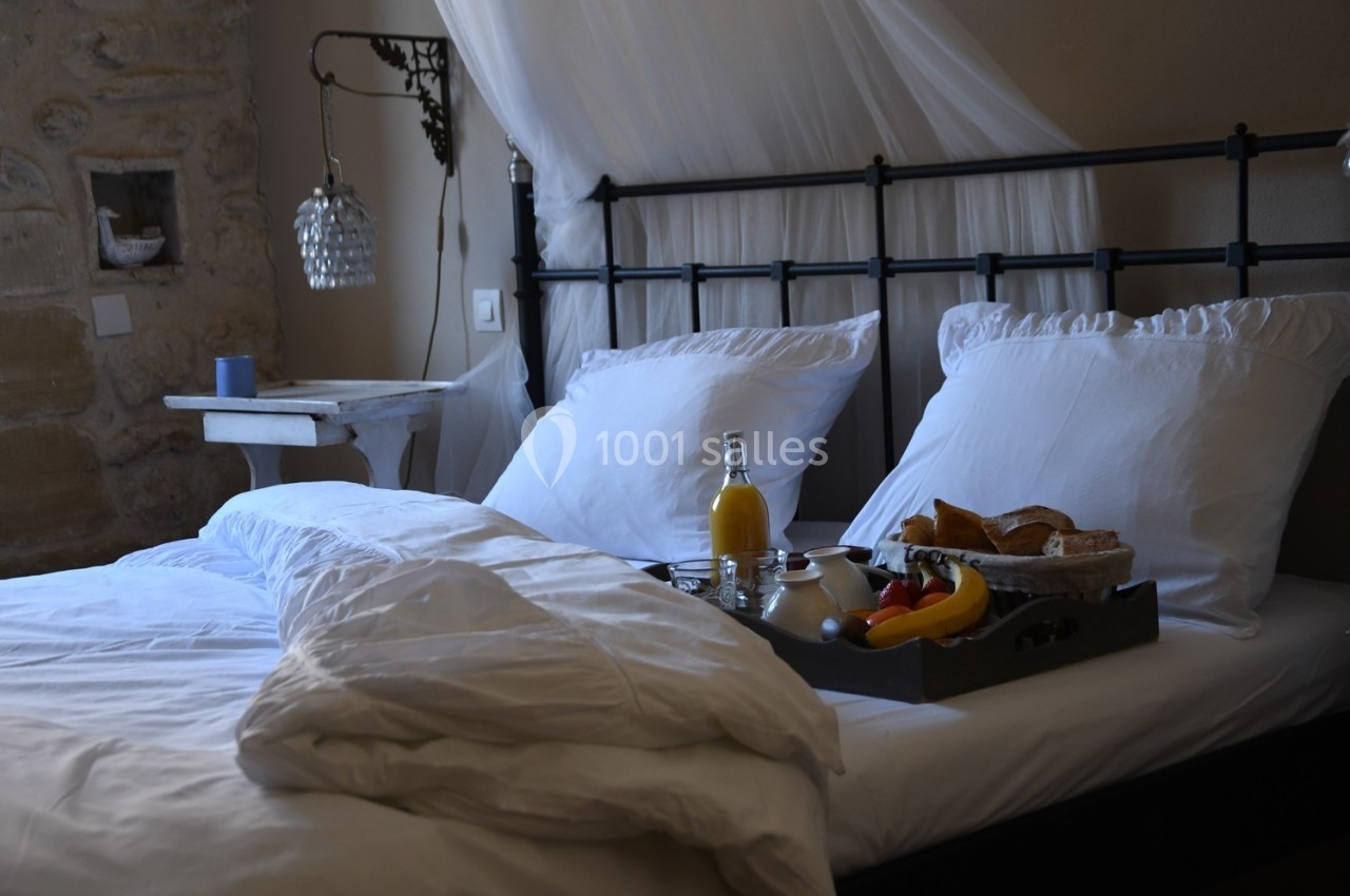 Plateau de petit-déjeuner avec fruits, jus d'orange et viennoiseries posé sur un lit avec draps blancs dans une chambre…