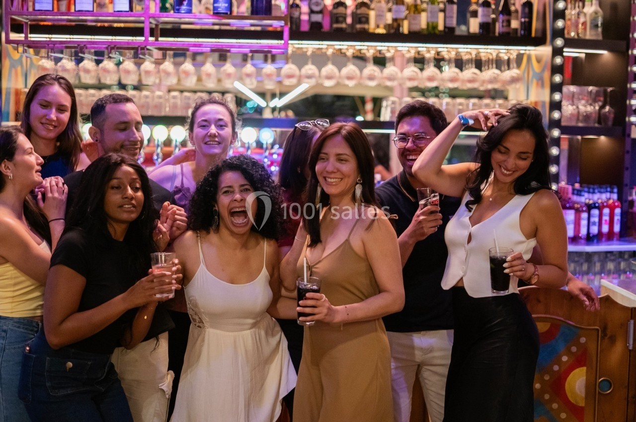 Groupe de personnes souriantes partageant un moment convivial dans un bar lumineux.