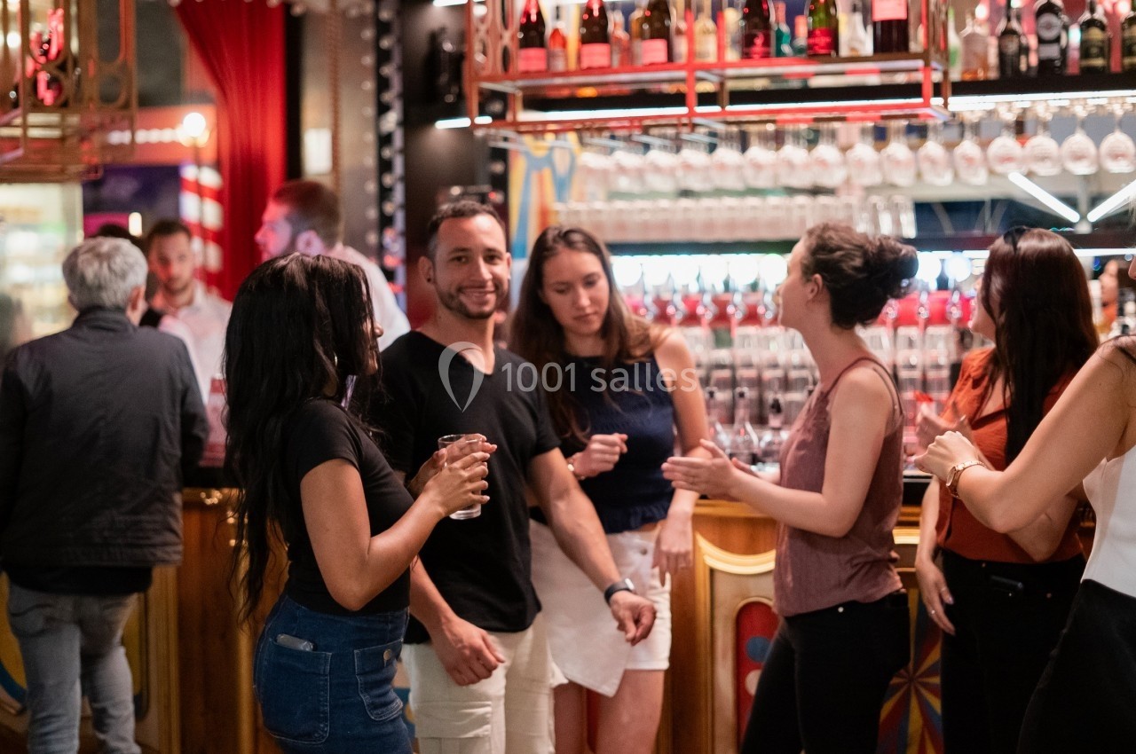 Groupe de personnes discutant et partageant un moment convivial près d'un bar lumineux.