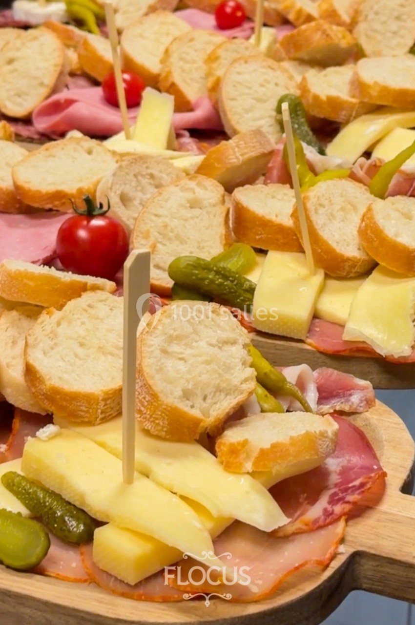Plateaux de charcuterie avec fromage, cornichons, tranches de pain et tomates cerises, présentés sur des planches en bois.