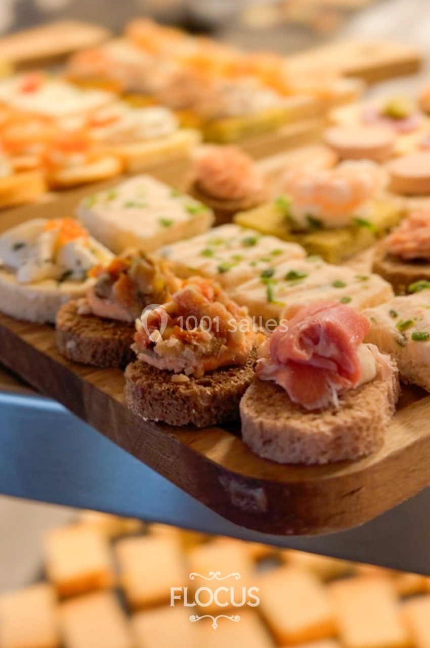 Plateau en bois garni de canapés variés, incluant charcuterie, crevettes et garnitures colorées.