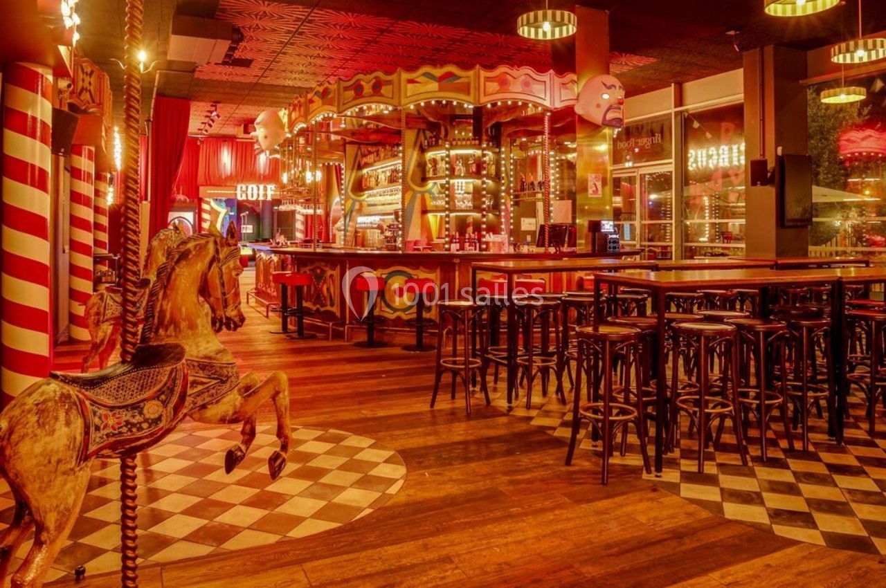 Intérieur d'un bar à thème avec décor de manège, chevaux en bois, tabourets et éclairage chaleureux.
