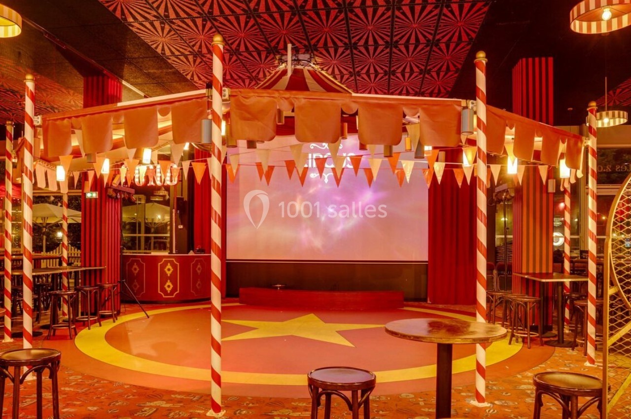 Intérieur d'une salle décorée sur le thème du cirque avec chapiteau, étoile au sol et chaises disposées autour.
