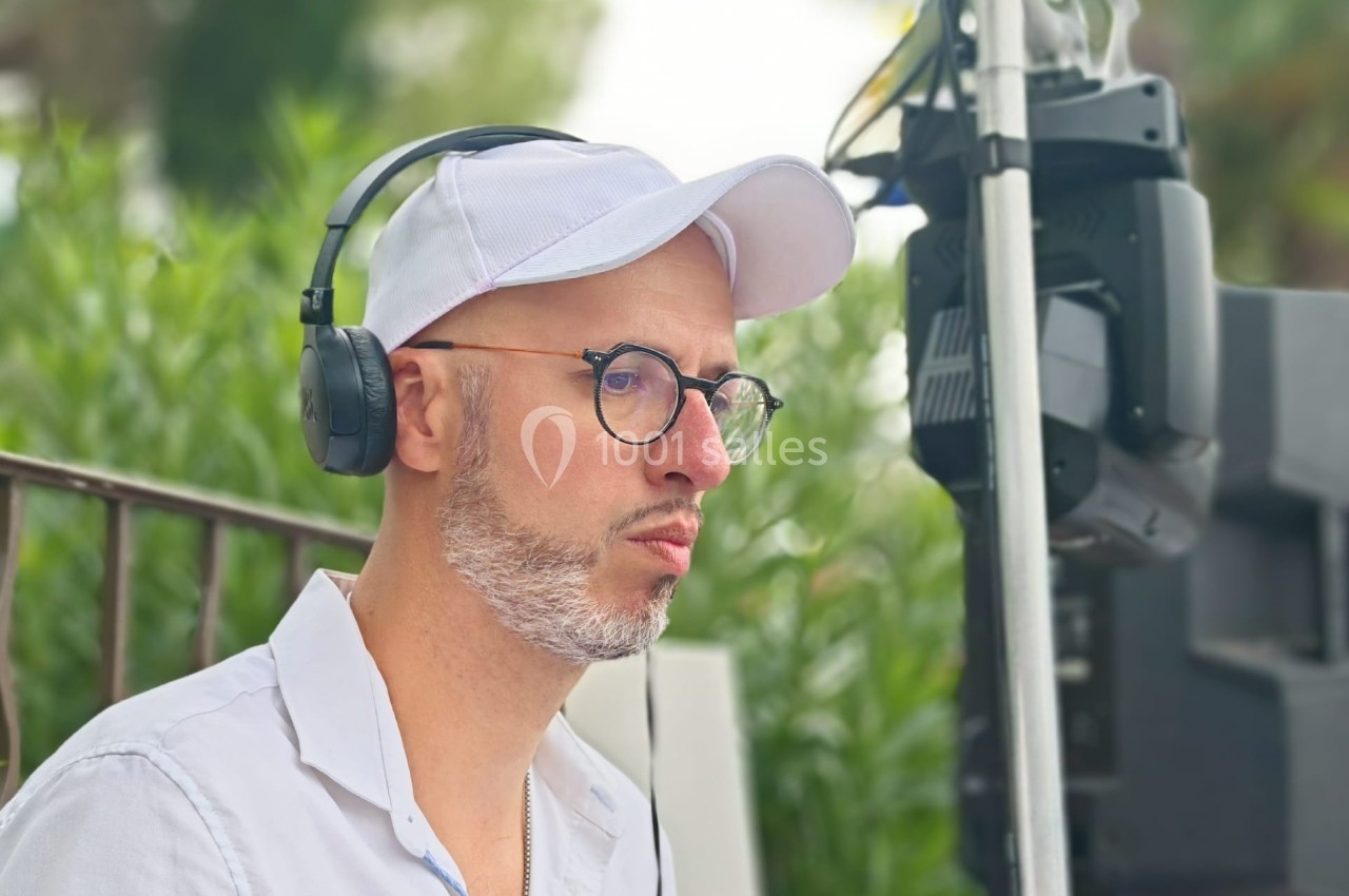 Homme portant un casque audio et une casquette blanche, concentré devant un équipement technique en extérieur.