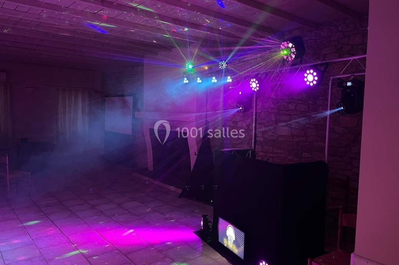 Jeux de lumières colorées et fumée dans une salle avec un équipement de sonorisation et un plafond en bois.