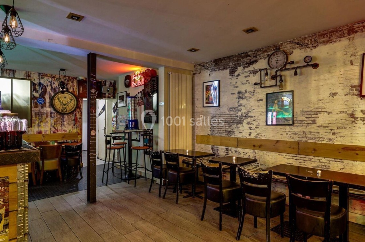 Intérieur d'un bar avec tables, chaises, décorations murales et éclairage chaleureux.