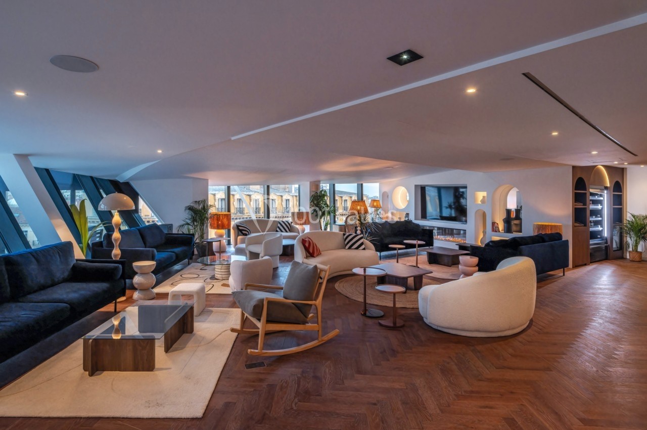 Salon spacieux et moderne avec mobilier design, parquet en bois, grandes fenêtres et éclairage chaleureux.