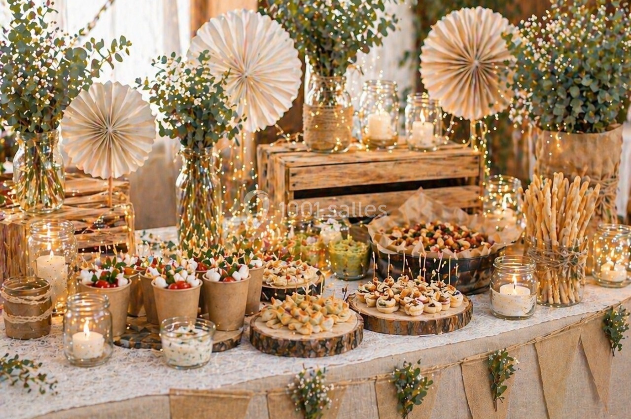Table décorée pour un buffet, avec des plats variés, des guirlandes lumineuses et des éléments naturels comme des branches d…