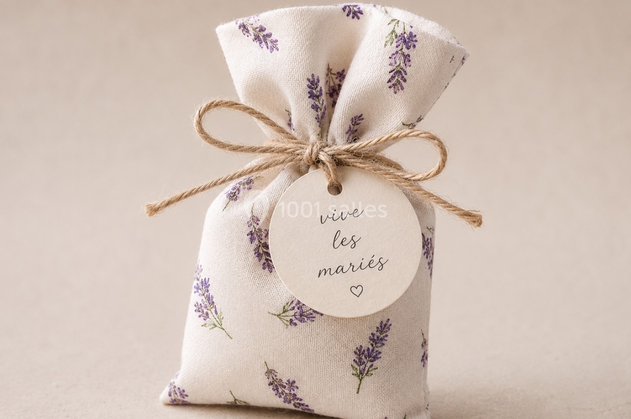 Petit sachet en tissu imprimé de lavande, fermé par une ficelle avec une étiquette portant l'inscription ’vive les mariés’.