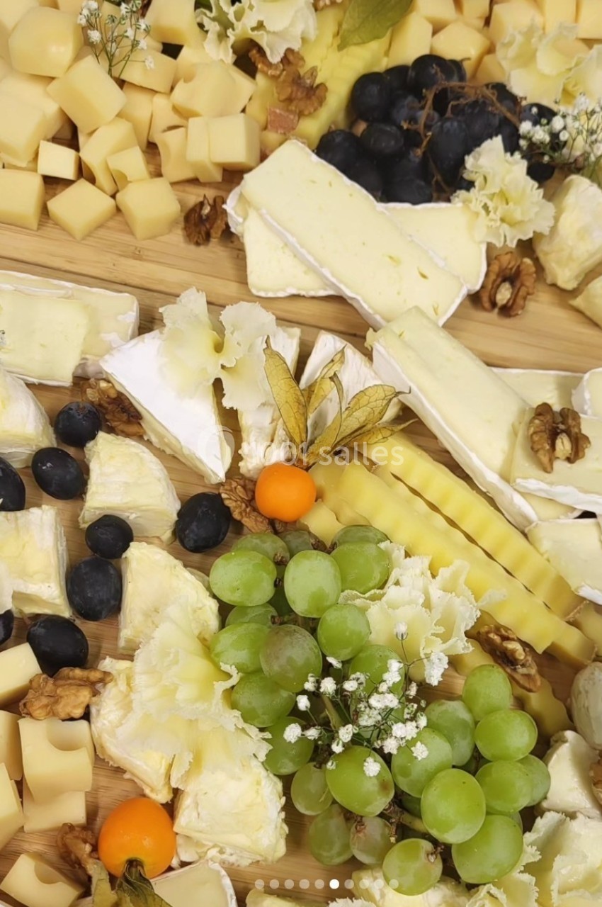 Plateau de fromages variés avec raisins, noix, physalis et décorations florales sur une planche en bois.