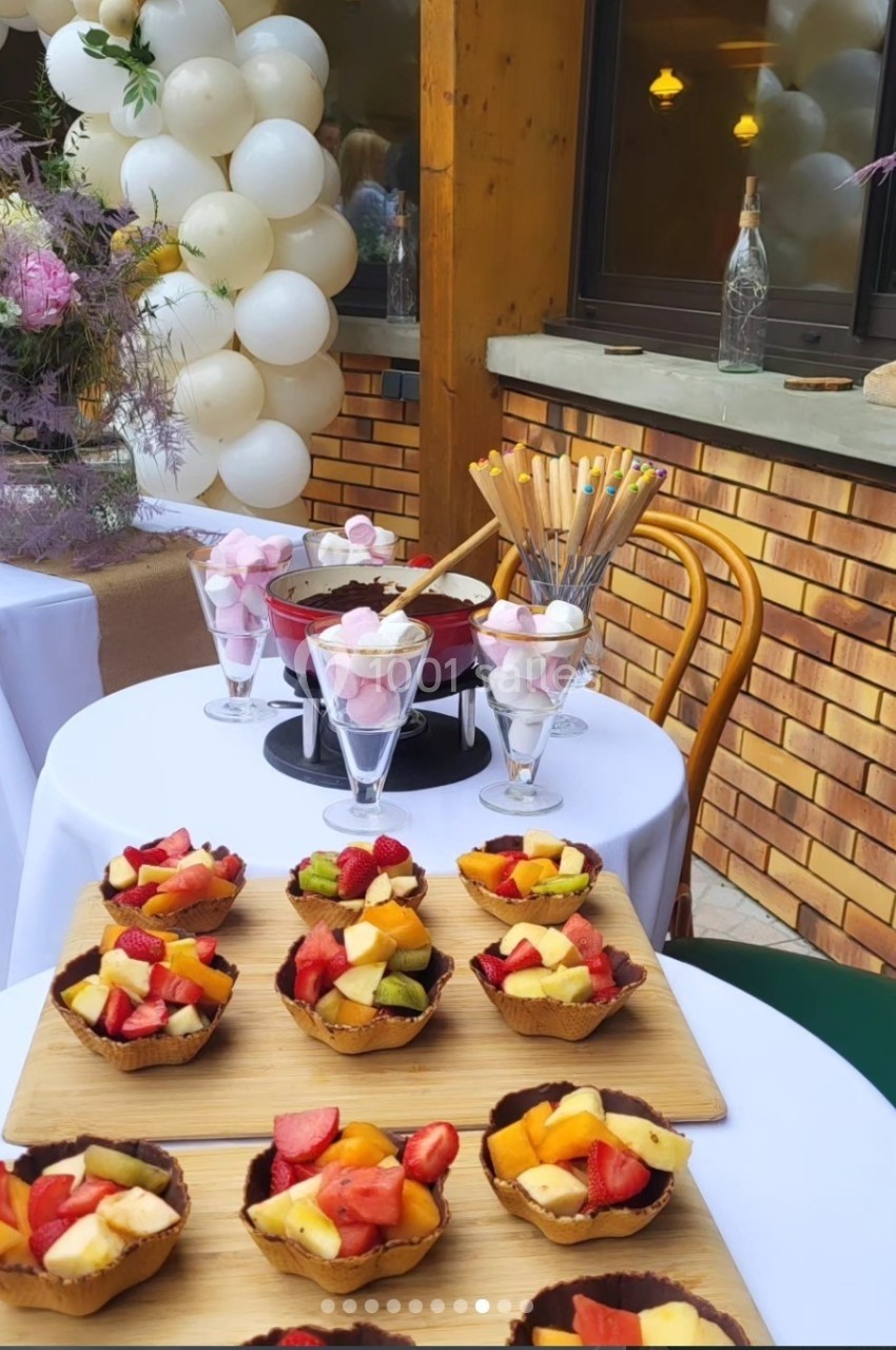 Desserts colorés à base de fruits frais et chocolats, disposés sur des planches en bois lors d'une réception en extérieur.