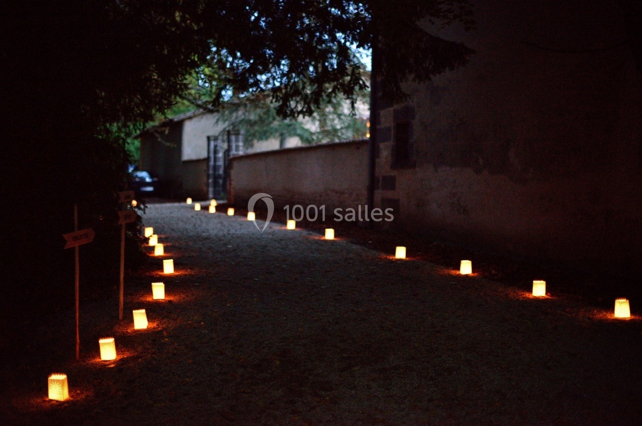 Allée sombre bordée de lanternes lumineuses posées au sol, créant une ambiance chaleureuse et paisible.