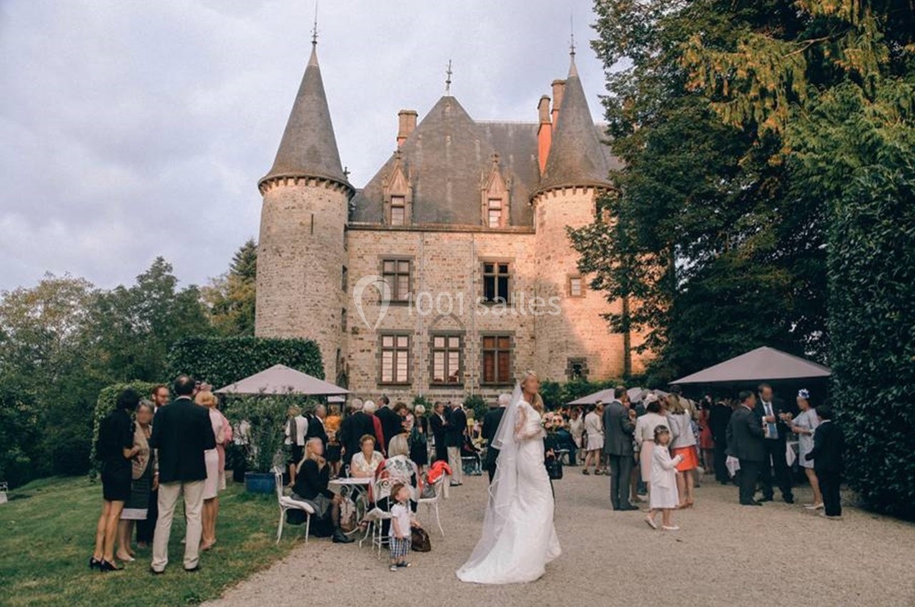 Groupe de personnes rassemblées devant un château en pierre avec des tours, lors d'un événement en plein air.