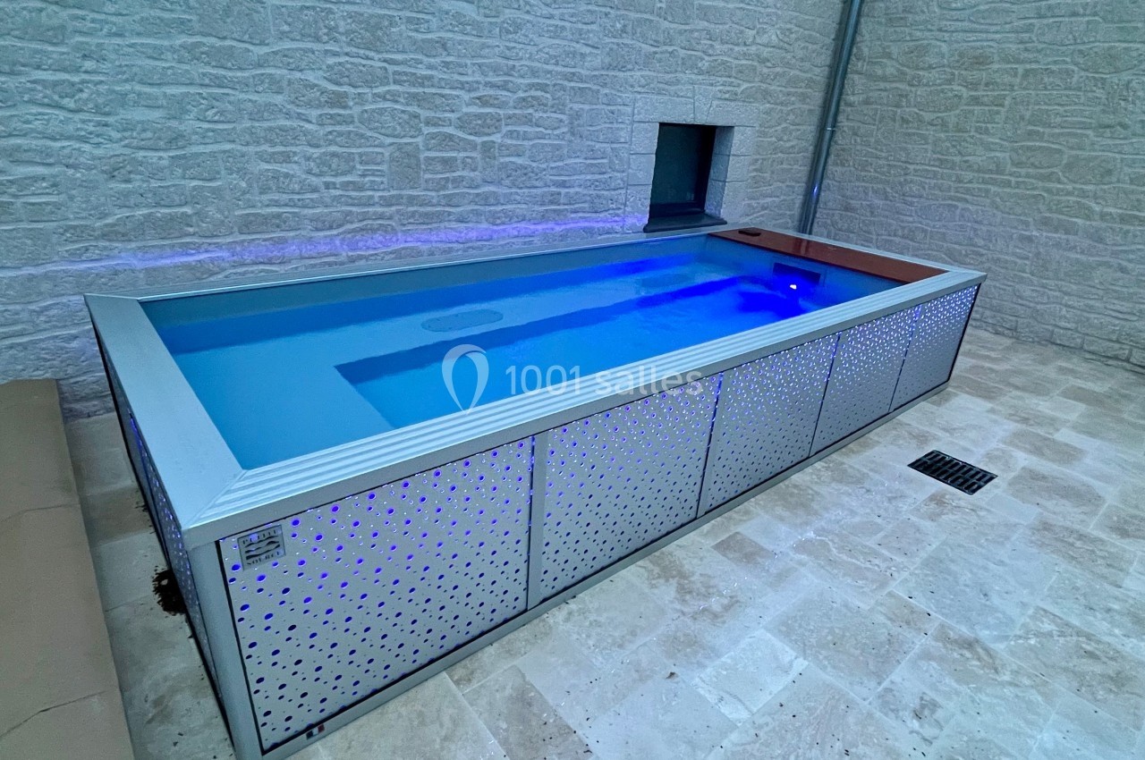 Piscine rectangulaire moderne avec parois métalliques perforées, située sur une terrasse en pierre.