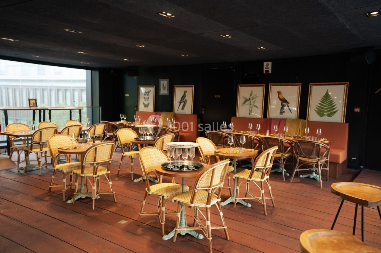Salle de restaurant avec chaises en rotin, tables rondes et décorations murales représentant des illustrations de nature.