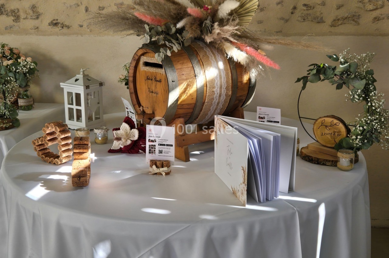 Table décorée pour un mariage avec tonneau en bois, livre d'or, lanternes et compositions florales.
