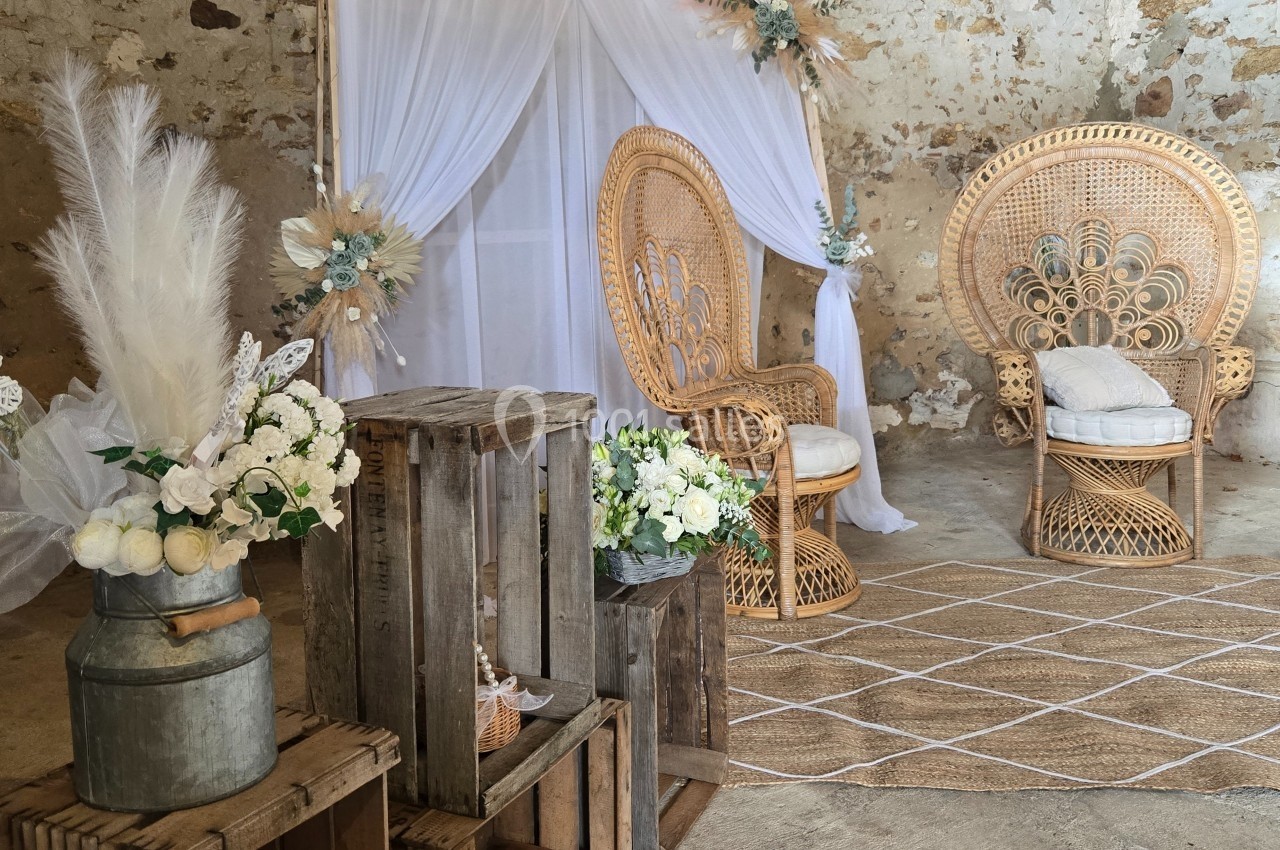 Décoration bohème avec fauteuils en rotin, fleurs blanches et éléments en bois dans un espace rustique.