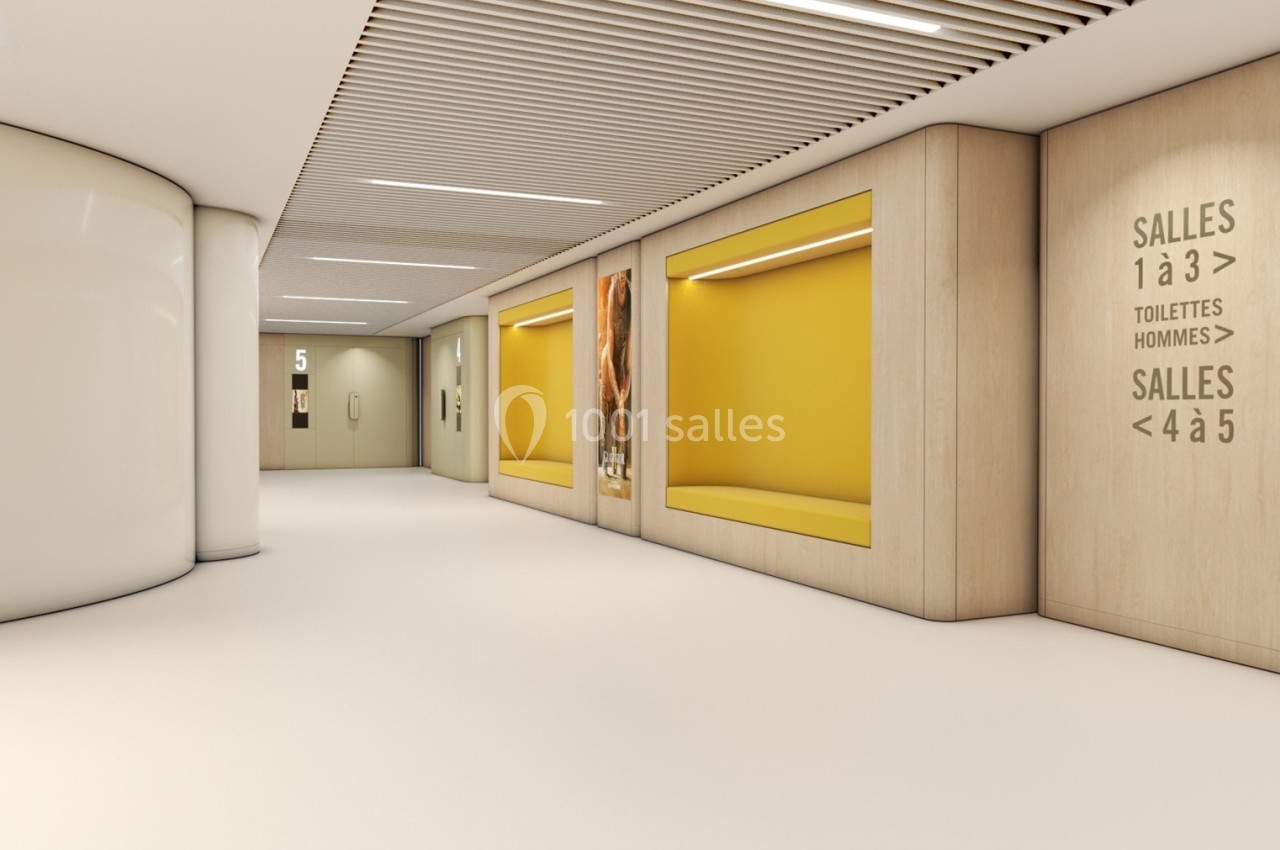 Couloir lumineux avec murs en bois clair, alcôves jaunes, signalétique pour salles et toilettes, et plafond à lames.