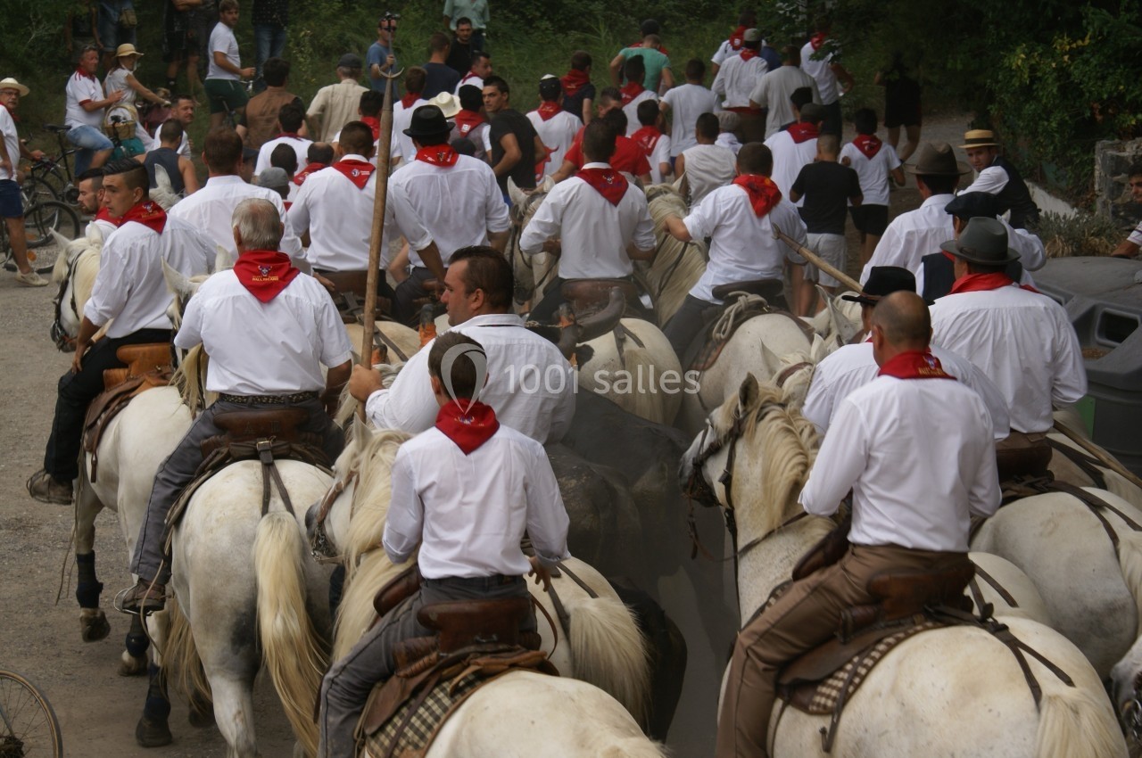 Groupe de cavaliers en chemises blanches et foulards rouges guidant des chevaux dans une rue animée.