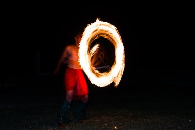 Un artiste jongle avec du feu dans l'obscurité, créant des motifs lumineux en mouvement.