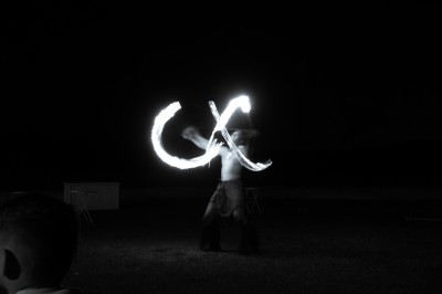 Un artiste jongle avec du feu dans l'obscurité, créant des motifs lumineux en mouvement.