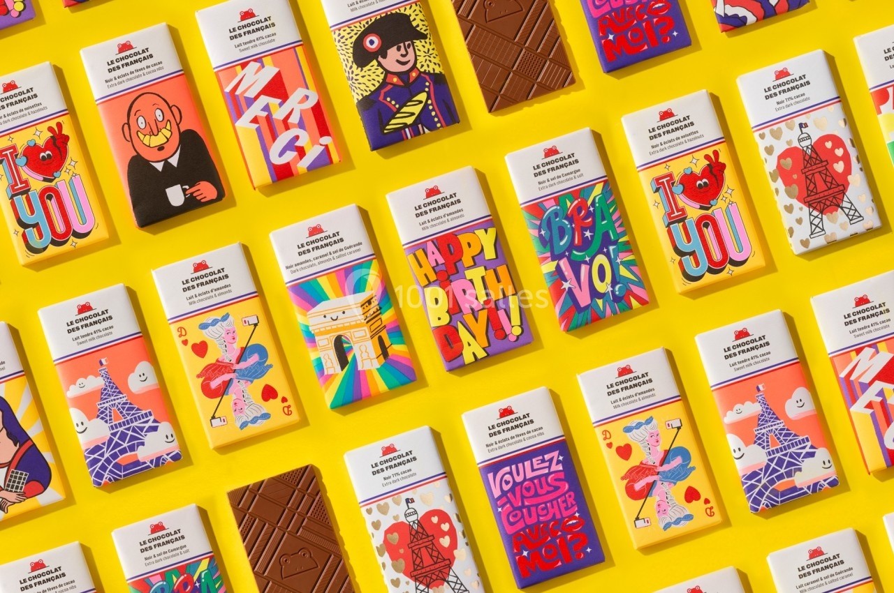 Tablettes de chocolat aux emballages colorés et illustrés, disposées en grille sur un fond jaune.