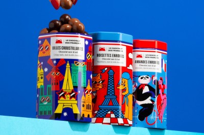 Chocolats colorés formant les mots ’Bonne Fête’ dans une boîte, une main prenant un carré décoré.