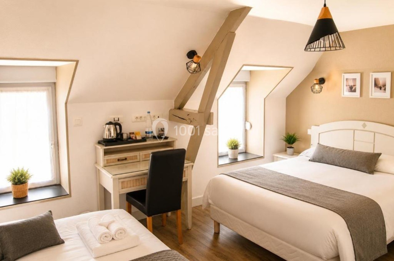 Chambre lumineuse avec deux lits, un bureau équipé d'une cafetière, des plantes et une décoration sobre.