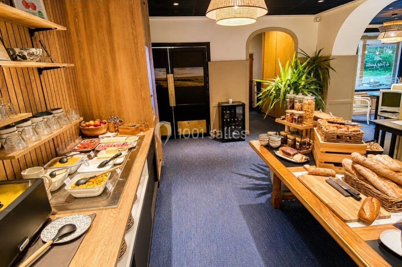 Buffet de petit-déjeuner avec pains, viennoiseries, fruits, céréales et plats chauds dans une salle lumineuse.