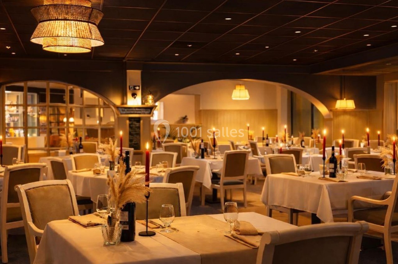 Salle de restaurant élégante avec tables dressées, chandelles allumées et éclairage tamisé.