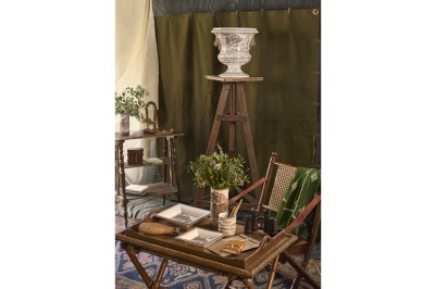 Intérieur décoré de style vintage avec table en bois, objets anciens, plantes et vase sur un chevalet.